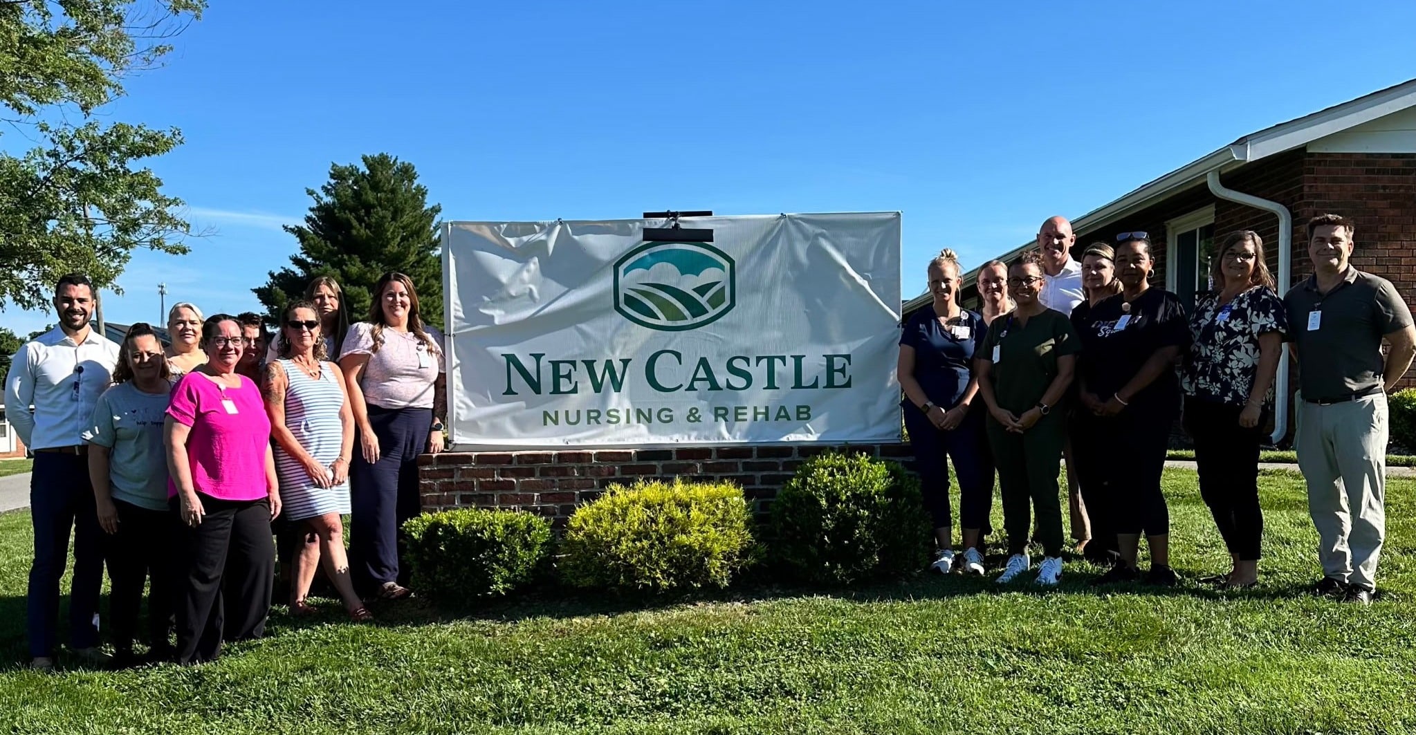 Newcastle Nursing & Rehab Staff standing next to sign